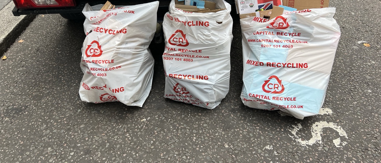 Three Capital Recycle mixed recycling sacks and flattened cardboard boxes at the rear of a caged tipper on a London street